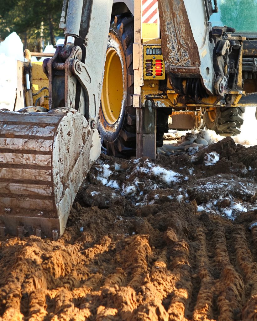 Bulldozer bucket close-up digs a pit for the construction. The foundation of the house, earthworks.